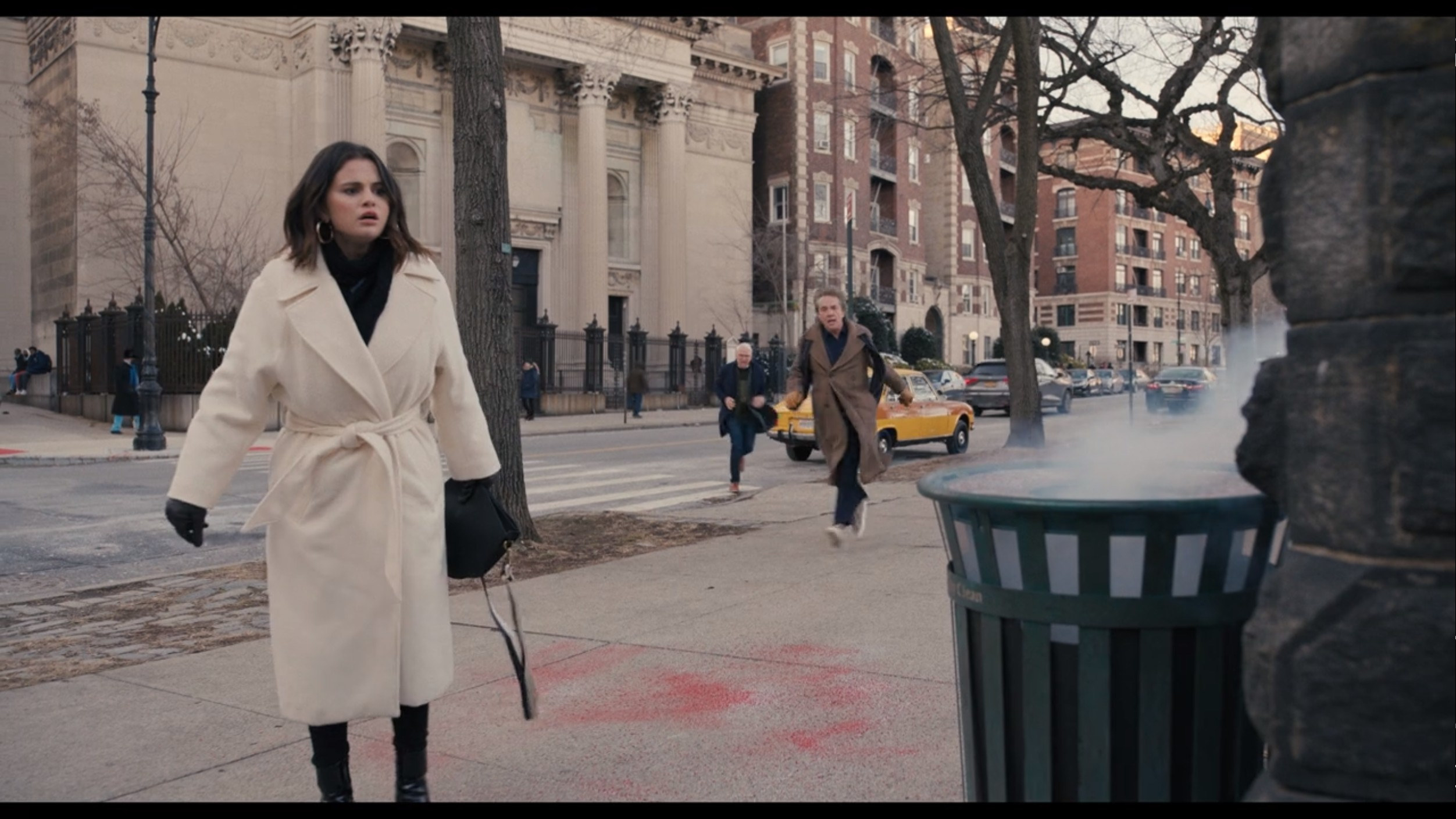 Mabel walking on the street in a white coat